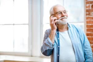 Senior man talks on the phone with a hearing aid specialist while wearing quality hearing aids
