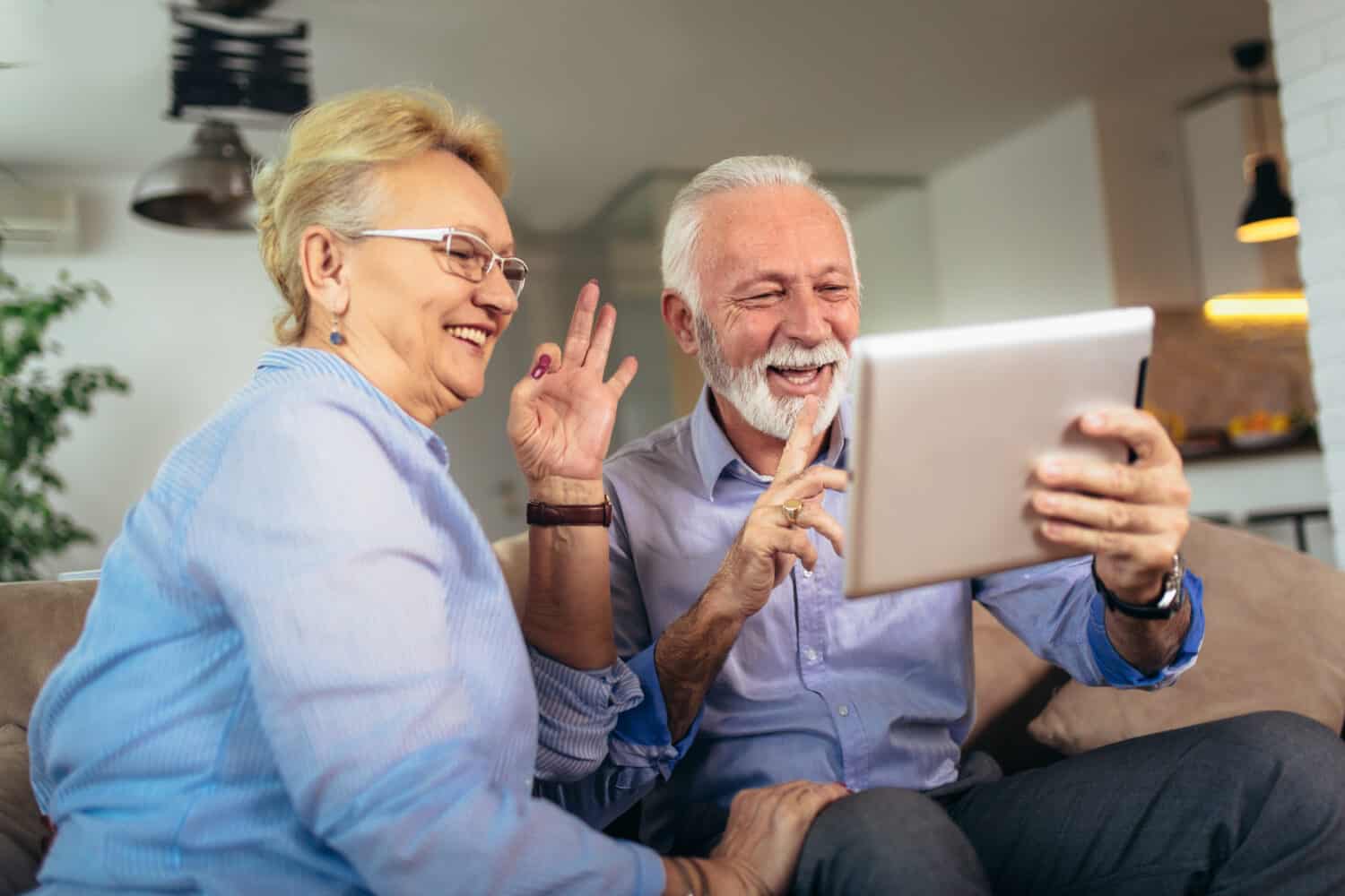 Smiling senior couple talk using visual cues on a video call with a hearing aid expert after taking the best online hearing test on the Lexie hearing website.