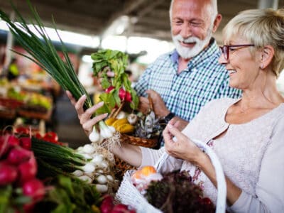 Mature couple shopping for groceries together both wearing invisible hearing aids.