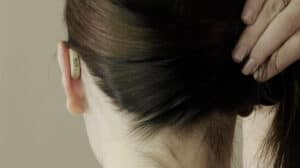 Woman wearing a very small, behind-the-ear Lexie hearing aid - the best hearing aid.