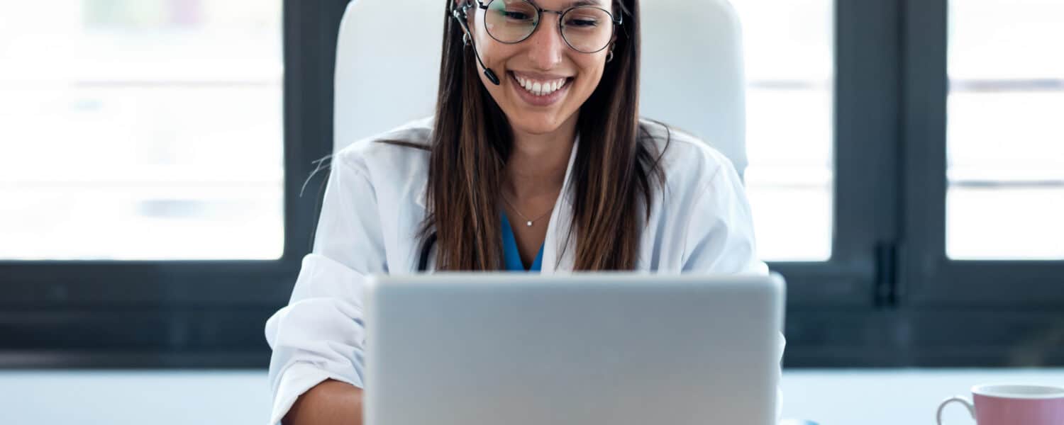 A hearing aid professional smiling while consulting with a customer on a video call