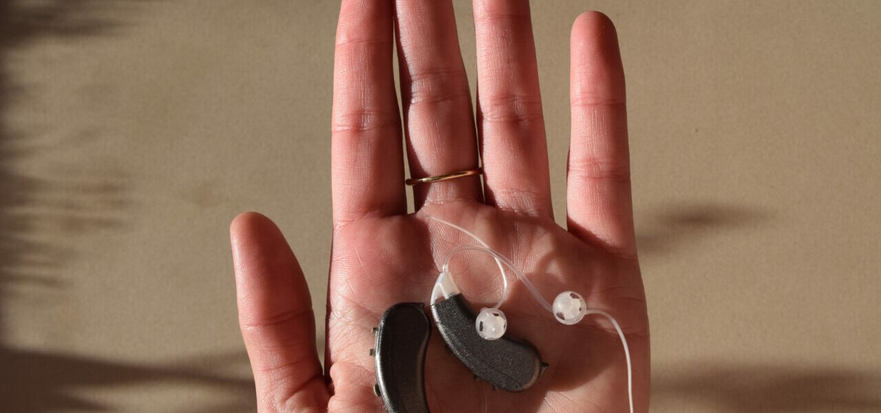 Woman holding Lexie Lumen hearing aids, sending the hearing aids for repair