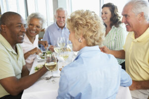 Elderly friends together at a restaurant, an environment where noise reduction in hearing aids can help