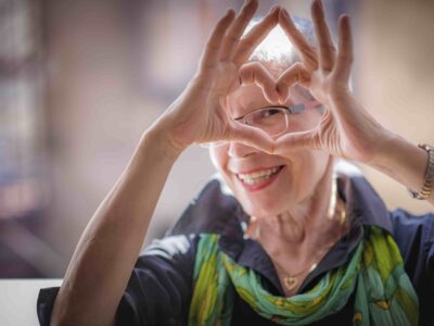 Senior woman making a heart shape with her hands after learning what to do with her old hearing aids