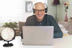 man sitting at his laptop with headphones on to take an online hearing test