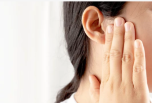 Woman holding her congested ear considering these tips on how to safely clean your ears