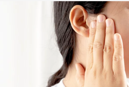 Woman holding her congested ear considering ear wax removal