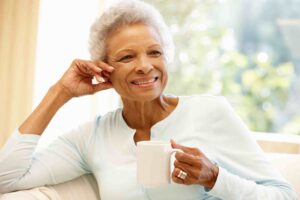 Woman drinking tea and smiling after healing her hearing loss