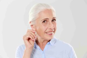 Senior woman holding her ear, thinking of hearing loss statistics