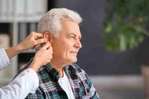 Hearing health practitioner fitting a hearing aid