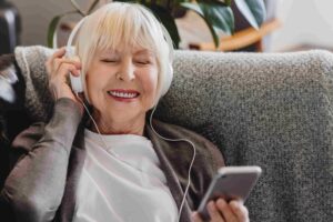 Senior woman listening on headphones wondering if do earbuds cause hearing loss.