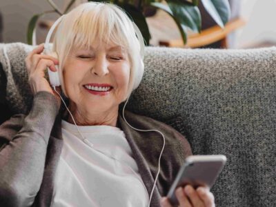 Senior woman listening on headphones wondering if do earbuds cause hearing loss.