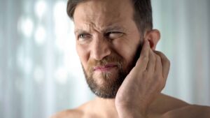 Man holding his ear as he has an ear infection