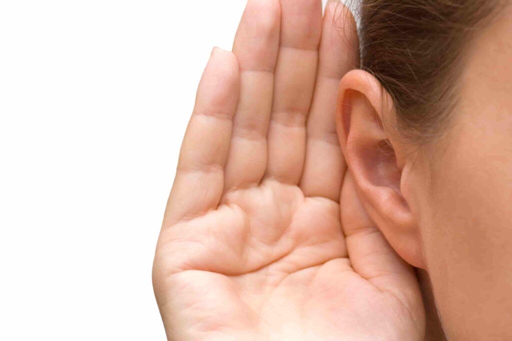 Woman holding her ear sharing hearing aid facts