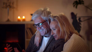 Happy romantic senior couple hugging and using digital tablet at home
