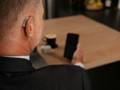 Man looking at phone with hearing aid in ear